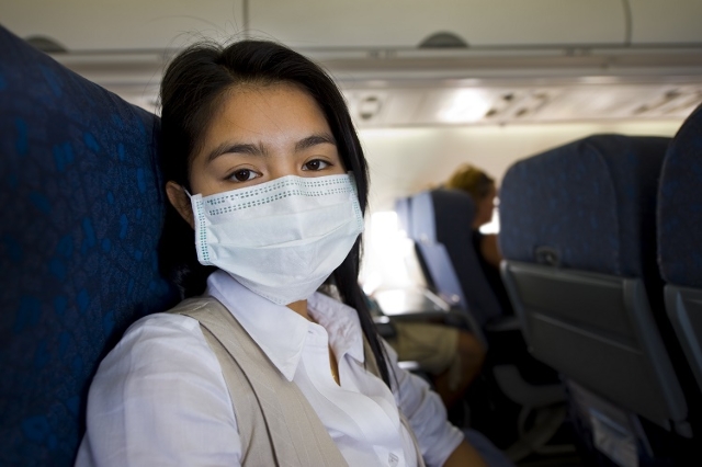 woman with protective mask in a plane (Thinkstock)