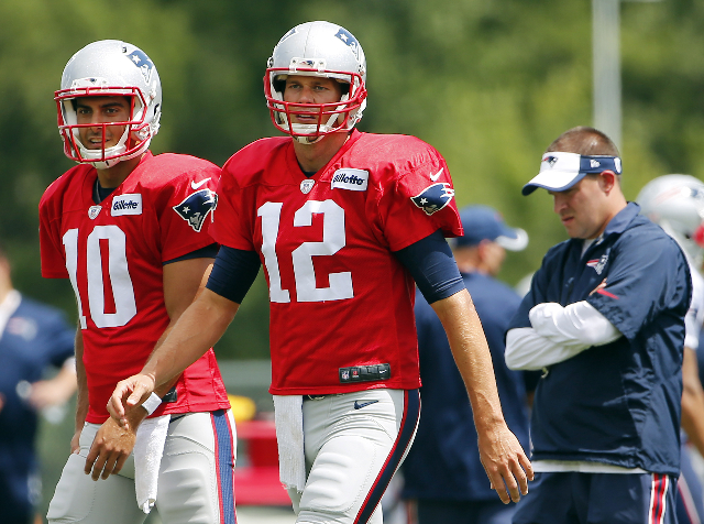 Aug 6, 2015; Foxborough, MA, USA; New England Patriots quarterback Tom Brady (12) and quarterback Jimmy Garoppolo (10) look on during training camp as offensive coordinator Josh McDaniels follows ...