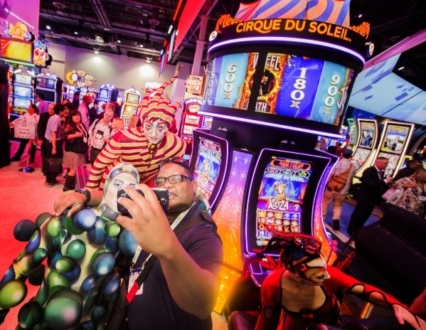Vander McInnis of Snoqualmie, Wash.  takes a selfie with  Cirque du Soleil performers in front of the newest Cirque du Soleil-themed slots at Scientific Games booth during the Global Gaming Expo a ...