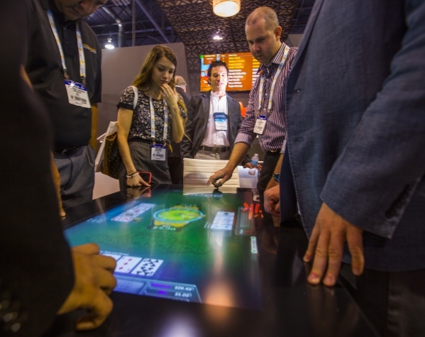 Eric Meyerhofer, center, CEO of Gamblit Gaming, watches people play a tabletop skill-based game in the Gamblit booth at the Global Gaming Expo in the Sands Expo and Convention Center on Wednesday, ...