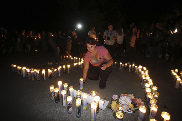 A woman places a candle as people take part in candle light vigil following a mass shooting at Umpqua Community College in Roseburg, Oregon October 1, 2015. A gunman opened fire at a community col ...