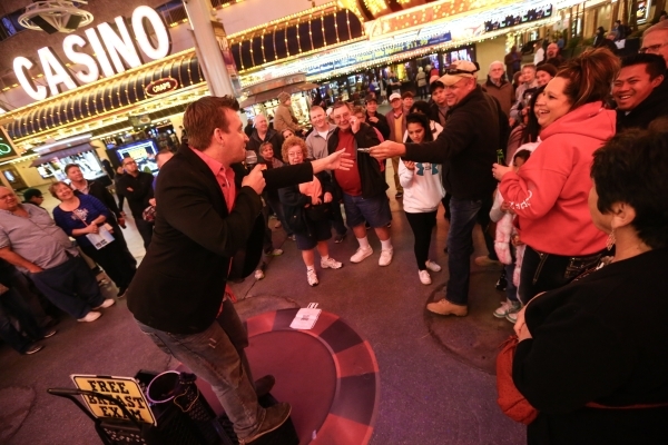 Magician Chris Randall, left, takes a $100 bill from Shawn Ferrel of Missouri, at the Fremont Street Experience in downtown Las Vegas on Tuesday, Nov. 17, 2015. Tuesday was the first day of the ci ...