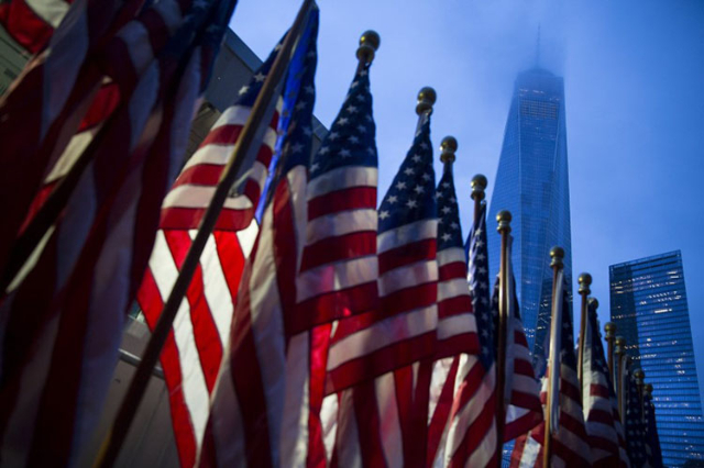 One World Trade Center is seen behind U.S flags on the morning of the 14th anniversary of the 9/11 attacks, in Lower Manhattan in New York September 11, 2015. . REUTERS/Andrew Kelly