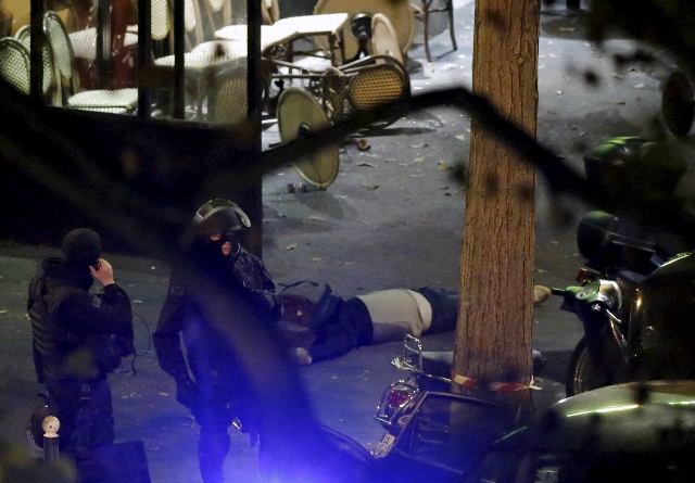 ATTENTION EDITORS - VISUAL COVERAGE OF SCENES OF INJURY OR DEATH French policemen stand next to a victim on the sidewalk outside a cafe near the Bataclan concert hall following fatal shootings in ...