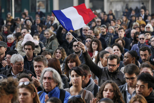 A man waves a French flag as several hundred people gather to observe a minute of silence in Lyon, France, November 16, 2015, to pay tribute to the victims of the series of deadly attacks in Paris ...