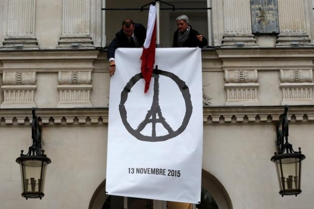 Municipal employees deploy a banner with the drawing "Peace for Paris" by French artist Jean Jullien as people observe a minute of silence at the city hall in Nantes, France, to pay trib ...