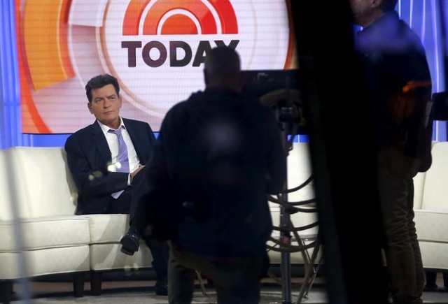 Actor Charlie Sheen, right, is seen through a window as he sits on the set of the NBC Today show prior to being interviewed by host Matt Lauer, Nov. 17, 2015. (Reuters/Mike Segar)