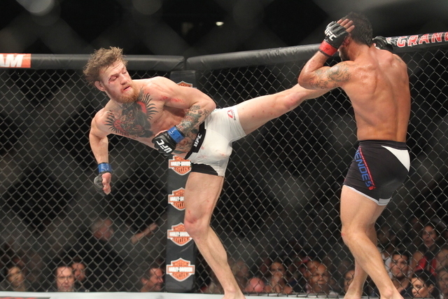 Conor McGregor, left, lands a kick against Chad Mendes during their interim featherweight title bout at UFC 189 at the MGM Grand Garden Arena Saturday, July 11, 2015, in Las Vegas. McGregor won by ...