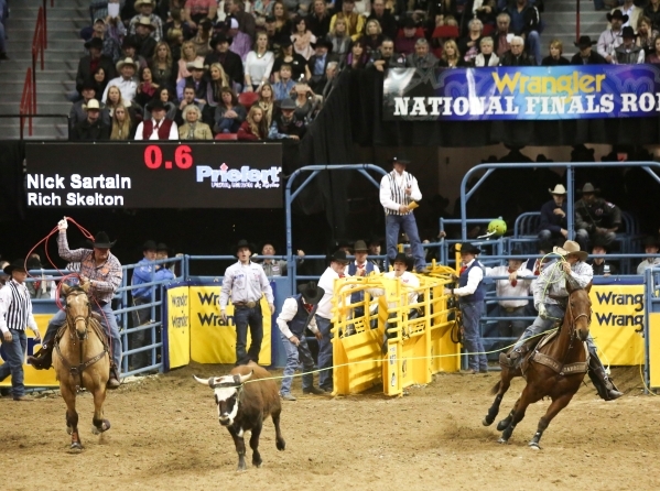 Nick Sartain, right, and Rich Kelton, left, rope a steer in the Team Roping competition on the second day of the 2015 Wrangler National Finals Rodeo at the Thomas & Mack Center in Las Vegas o ...