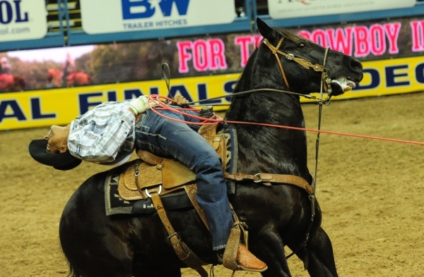 Team roper Junior Nogueira from Scottsdale, Ariz., pulls a rope tight on a calf a calf during the first go-round of the 2015 Wrangler National Finals Rodeo at the Thomas & Mack Center in Las V ...