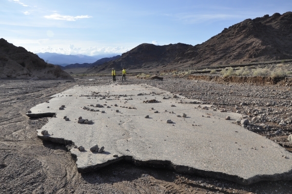 Workers survey the damage from an October flash flood along Badwater Road near Jubilee Pass in Death Valley National Park. The road is expected to remain closed until June between Shoshone, Calif. ...