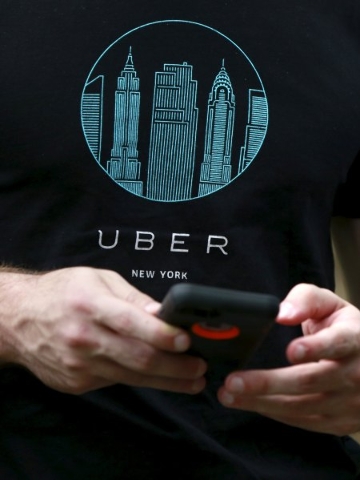 An Uber representative registers people on his smartphone Tuesday during the kick off of a citywide jobs tour in the Queens borough of New York.  (Shannon Stapleton/Reuters)