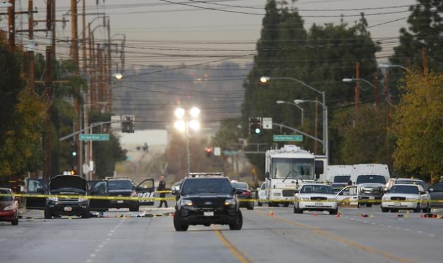Police vehicles line the street around a vehicle (L) in which two suspects were shot following a mass shooting in San Bernardino, California December 3, 2015. REUTERS/Mike Blake
