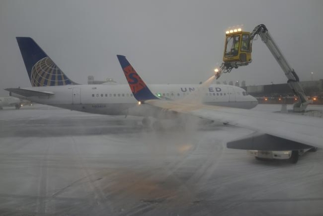 A Sun Country Airlines plane‘s wing is de-iced as a United Airlines plane waits at the de-icing station during a snowstorm at Logan International Airport in Boston, Massachusetts, United Sta ...