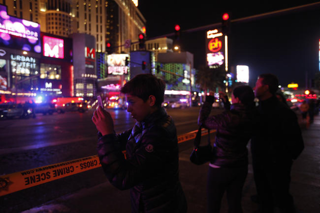 Bystanders watch as police investigate the scene of a crash on the Strip in Las Vegas that left one person dead and 37 injured after a car plowed into a group of pedestrians the evening of Sunday, ...