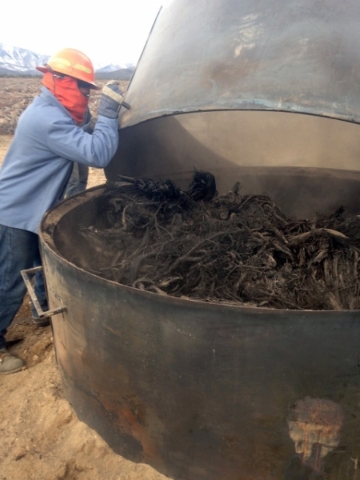 A Nevada Division of Forestry crew member prepares to collect charred pieces of pinion-juniper trees from inside a kiln near Ely on Dec. 9, 2015. The process is an experiment on how to utilize for ...