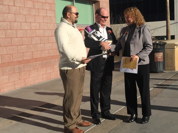 Clark County Clerk Lynn Goya, right, presents Dumitru Alexeev, left, and his husband Ronald Bauman, center, with gifts on Friday, Jan. 1, 2015, to celebrate their marriage and the fact that they a ...