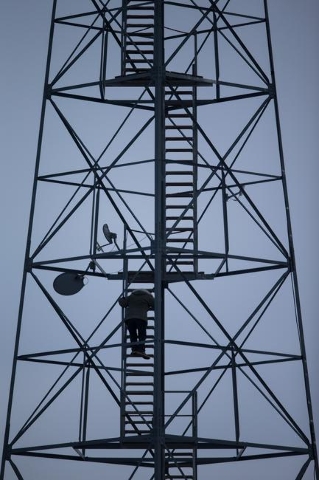 An anti-government protestor climbs down from a watch tower near by the entrance of Malheur National Wildlife Refuge headquarters, which is occupied by the group, near Burns, Ore. on Monday, Jan. ...