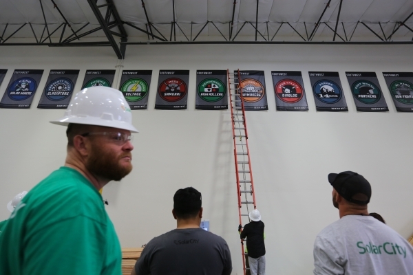 Workers watch as the banners celebrating SolarCity‘s installation crews across the U.S. are pulled down at the SolarCity training facility in Las Vegas on Tuesday, Jan. 5, 2016. SolarCity de ...
