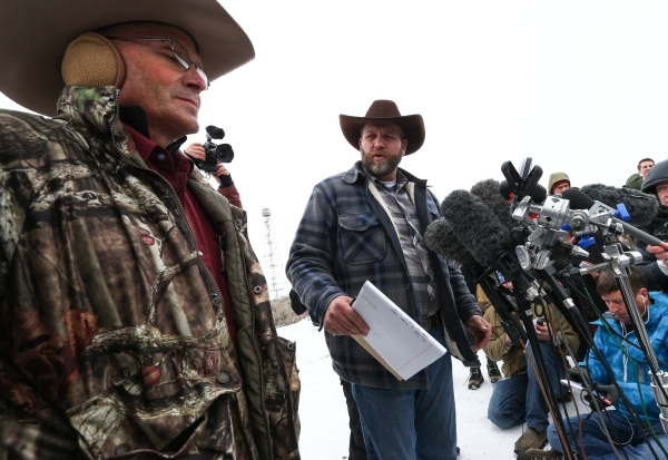 Ammon Bundy, right, motions to Arizona Rancher LaVoy Finicum, left, while speaking with reporters at a news conference by the entrance of Malheur National Wildlife Refuge headquarters near Burns,  ...