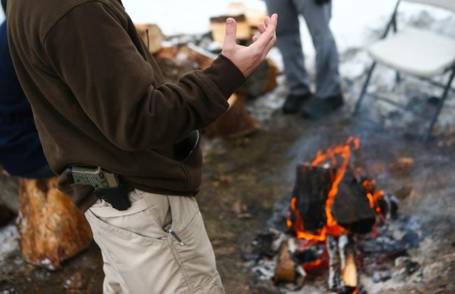 Anti-government protester Jon Ritzheimer talks by a fire while guarding the entrance of the Malheur National Wildlife Refuge headquarters, which the group is occupying, near Burns, Ore. on Thursda ...