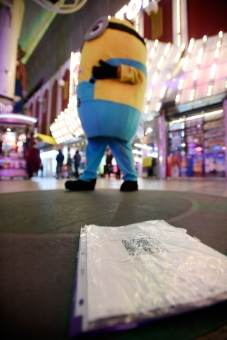 A registration certificate lies on the ground where a Minion character encourages people to pose for pictures at the Fremont Street Experience Monday, Jan. 11, 2016, in Las Vegas. Buskers such as  ...