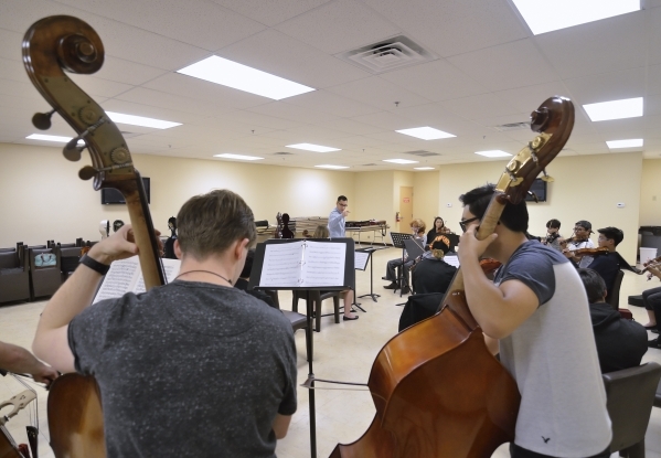 Bass players Daniel Skurski, left, and Joshua Riel perform as Yunior Lopez, center background, conducts during a Young Artists Orchestra rehearsal at the Adelson Clinic at 3661 Maryland Parkway in ...