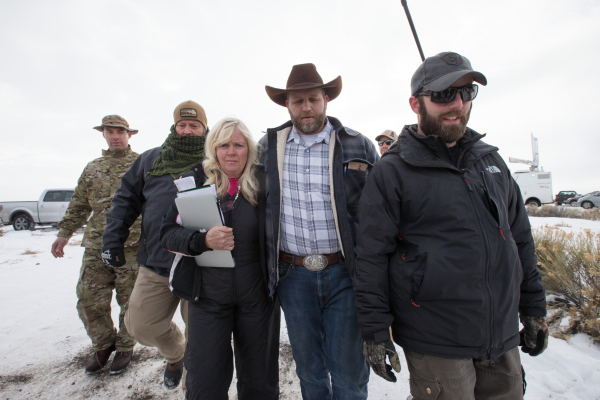 Ammon Bundy, center right, with Shawna Cox, walks with supporters after speaking with reporters at a news conference by the entrance of Malheur National Wildlife Refuge near Burns, Ore. on Monday, ...
