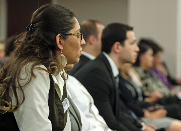 Boulder Station employee Yesenia Quintana, left, sits in a crowded room an attends a Gaming Control Board hearing at Grant Sawyer building Thursday, Jan. 21, 2016, in Las Vegas. The board signed o ...
