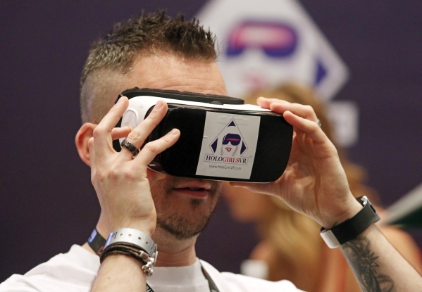 Show exhibitor Ed Collins looks through a device that allows the view to see virtual reality pornography at the Holo Film Productions booth during the AVN Adult Entertainment Expo 2016 at Hard Roc ...