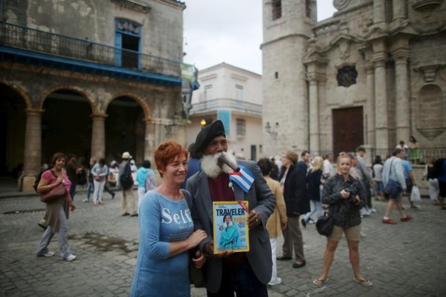 Hermenegildo Arensivia, 61, (R), takes a picture with a tourist from Poland in old Havana in this January 13, 2016 picture. REUTERS/Alexandre Meneghini