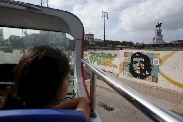 A tourist from Peru looks at a graffiti of revolutionary hero Ernesto "Che" Guevara from the top of a double decker sightseeing bus in Havana in this January 17, 2016 picture. REUTERS/Al ...