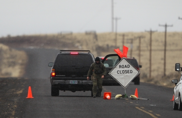 An FBI agent walks by a roadblock near the Malheur National Wildlife Refuge headquarters, where four anti-government protesters remain, about 30 miles south of Burns, Ore., on Friday, Jan. 29, 201 ...