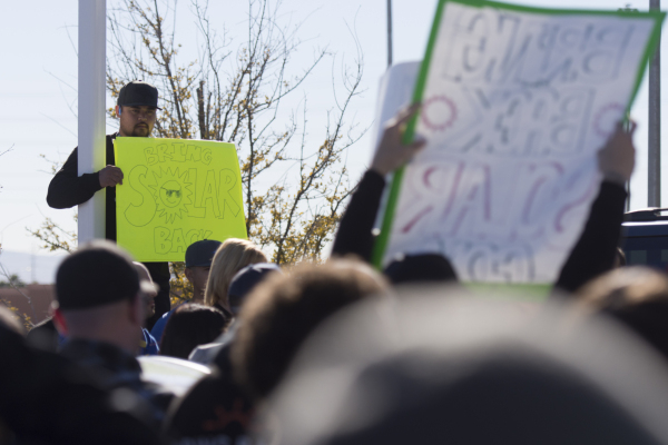 SolarCity Installer Ejay Santos, left, holds a sign above the crowd of solar workers and supporters protesting outside of the Public Utilities Commission office at 9075 W. Diablo Dr. in Las Vegas ...