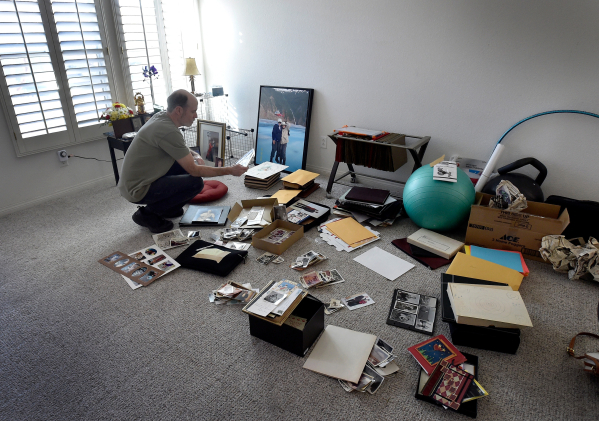 Larry Demetriades looks over family photographs in the Henderson home of his father-in-law, Oliver Phillips, Tuesday, Feb. 9, 2016. Phillips, 85, died in January from injuries from a beating in hi ...