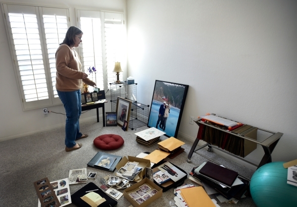 Laura Demetriades stands over family photographs in the Henderson home of her father, Oliver Phillips, Tuesday, Feb. 9, 2016. Phillips, 85, died in January from injuries from a beating in his home ...