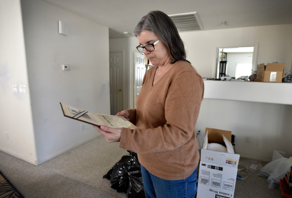 Laura Demetriades looks over a diploma her father earned while cleaning up the Henderson home of her father, Oliver Phillips, Tuesday, Feb. 9, 2016. Phillips, 85, died in January from injuries fro ...