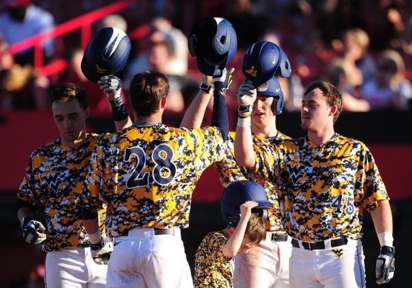 West Virginia‘s Cole Austin high fives teammates after hitting a three-run home run in the eighth inning of their NCAA college Baseball game against UNLV at Earl E. Wilson Stadium in Las Veg ...