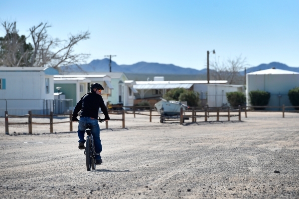 A resident travels along one of the dirt roads on his bicycle Thursday, Feb. 25, 2016, in Cal-Nev-Ari. The small community uses ATVs and bicycles as preferred modes of transportation throughout th ...