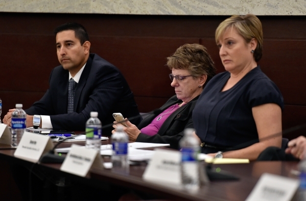 Julie Arnold, center, of the Southern Nevada Senior Law Program, refers to her mobile device as Jay Raman, left, of the Clark County District Attorney‘s office and Susan Hoy of Nevada Guardi ...