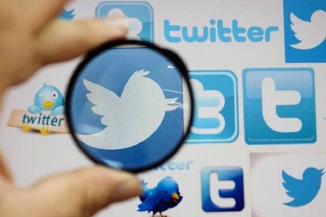 A person holds a magnifying glass over a computer screen displaying Twitter logos, in this picture illustration taken in Skopje September 10, 2013. (Reuters/Ognen Teofilovski)