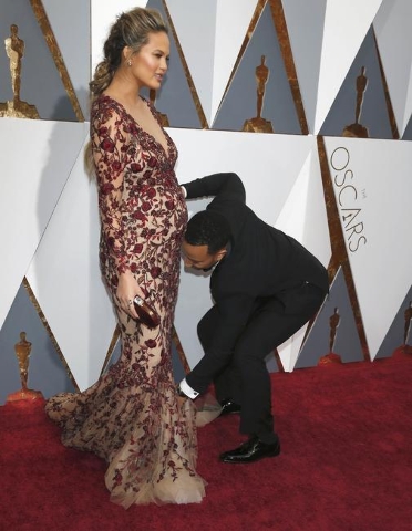 Model Chrissy Teigen has her dress adjusted by musician husband John Legend at the 88th Academy Awards in Hollywood, California February 28, 2016.  REUTERS/Adrees Latif
