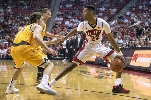 UNLV guard Patrick McCaw (22) is defended by Wyoming guard Jeremy Lieberman (11) and Wyoming guard Josh Adams (14) during the first half at the Thomas & Mack Center in Las Vegas on Saturday, F ...