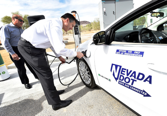 Gov. Brian Sandoval plugs in an all-electric vehicle after arriving at the dedication of the first electric car charging station along U.S. Highway 95 on Tuesday in Beatty. The station is the fist ...