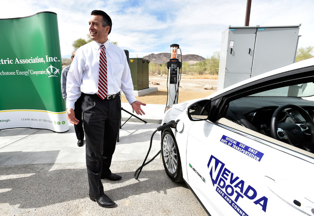 Nevada Gov. Brian Sandoval reacts to how easy it was to plug-in an all-electric vehicle after arriving at the dedication of the first electric car charging station along U.S. Highway 95 Tuesday, M ...