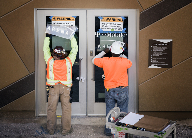 Workmen place signage on doors at theT-Mobile Arena behind New York-New York on Monday, Feb. 29, 2016. The joint venture partners AEG and MGM Resorts is scheduled to open the arena next month. Jef ...