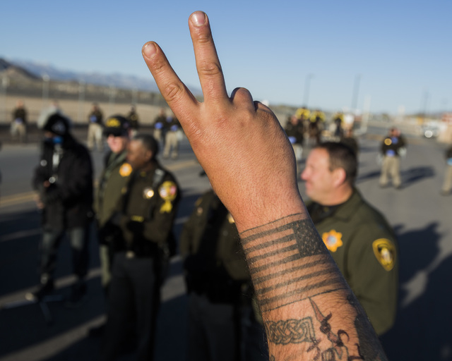 Former serviceman Jason Maluhia raises a peace sign shortly before he is arrested by Las Vegas police at the south entrance to Creech Air Force Base at Indian Springs on Friday, March 6, 2015. Thi ...