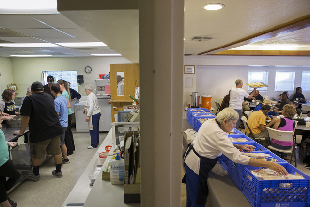 Dinner is prepared, left, in one room while the grocery line is organized by volunteers, right, by Friends in the Desert at St. Timothy’s Episcopal Church March 22. Benjamin Hager/View