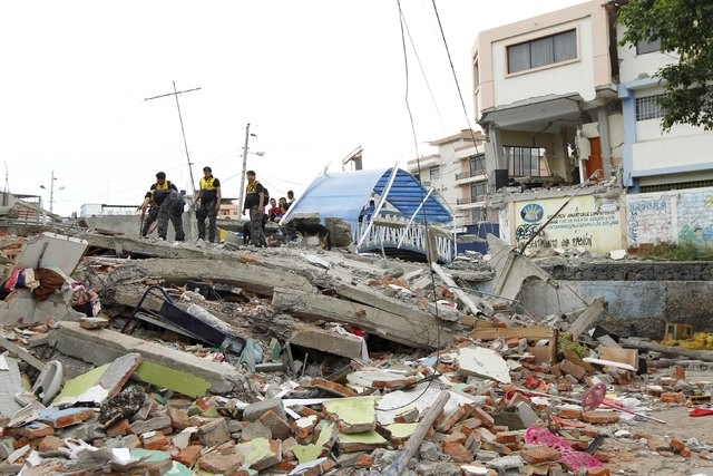 Police officers stand on debris after an earthquake struck off Ecuador's Pacific coast, at Tarqui neighborhood in Manta April 17, 2016.(Guillermo Granja/Reuters)