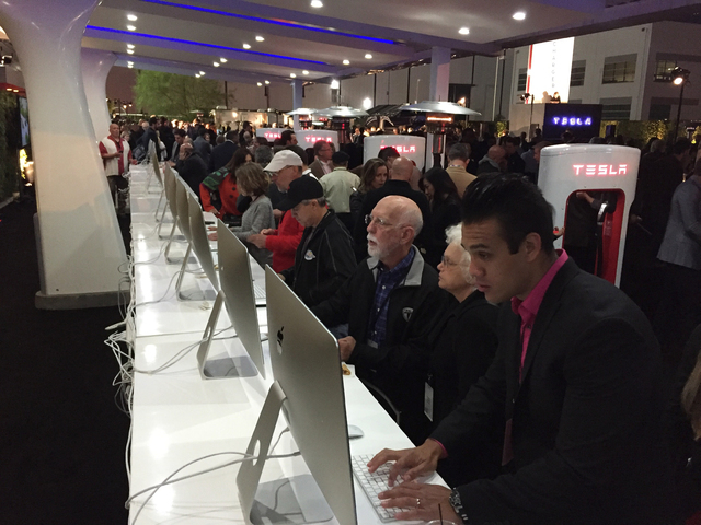 People sit at computers where they can reserve one of the cars before Tesla Motors unveils the Model 3 at the Tesla Motors design studio Thursday, March 31, 2016, in Hawthorne, Calif. (AP Photo/Ju ...
